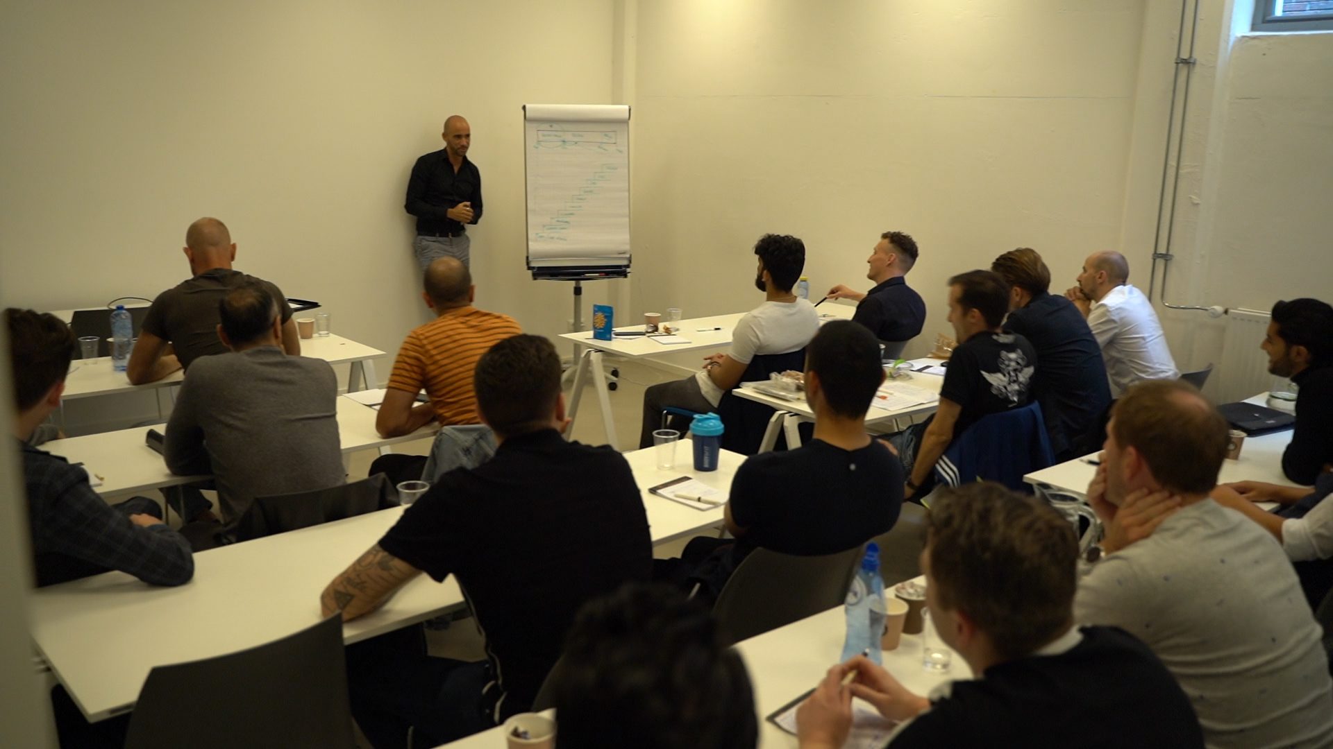 Rienk Bauritius geeft een live training aan een zaal mannen, met een flip-over op de achtergrond